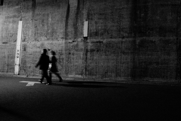 Figures walking in front of wall