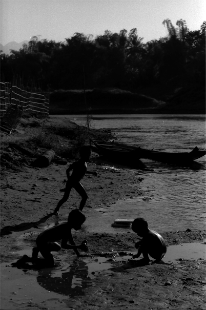 Silhouettes Of Three Kids Playing On The Dry Riverbed (Laos)