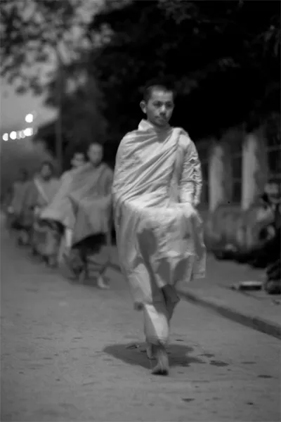 Buddhist monks walking dim street for alms
