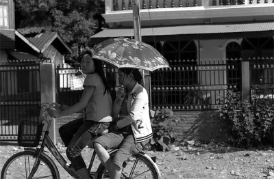 Two girl on same bicycle with sunshade