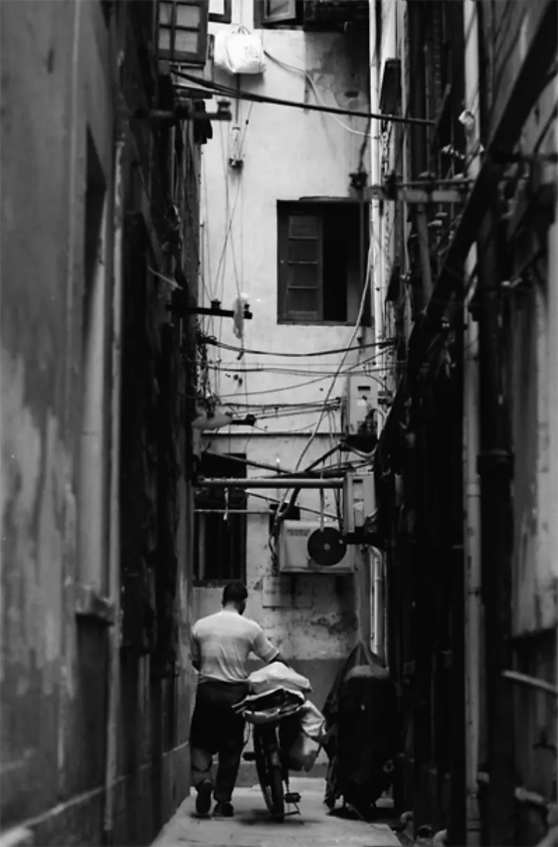 Man walking bicycle in dim lane