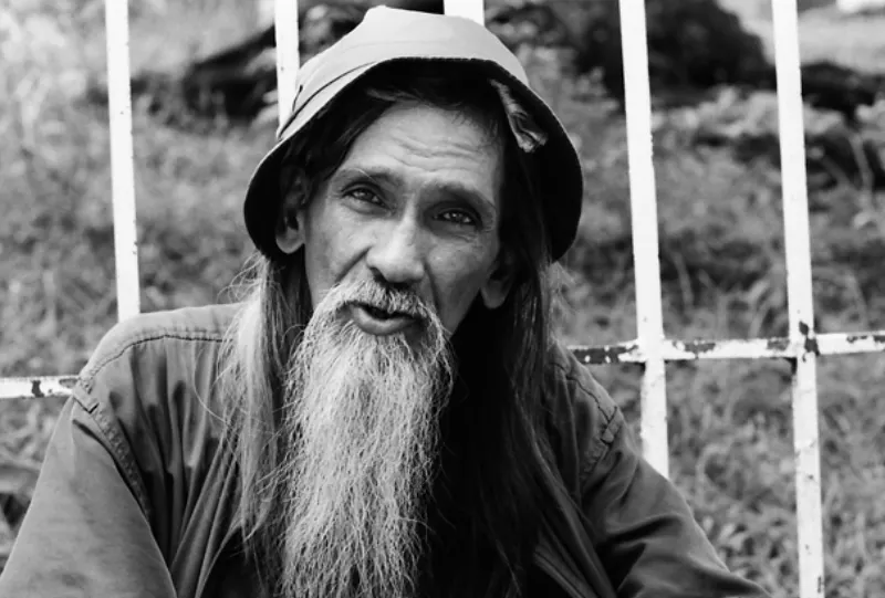 Bearded man sitting down by wayside