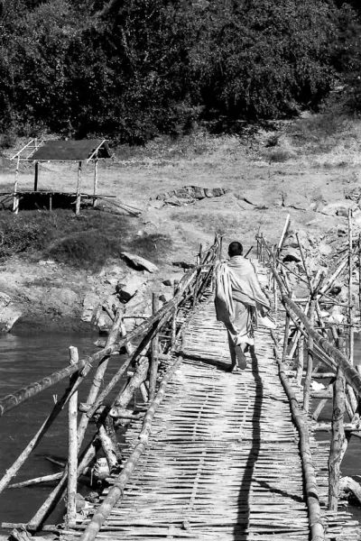 竹で組まれた橋を渡る僧侶