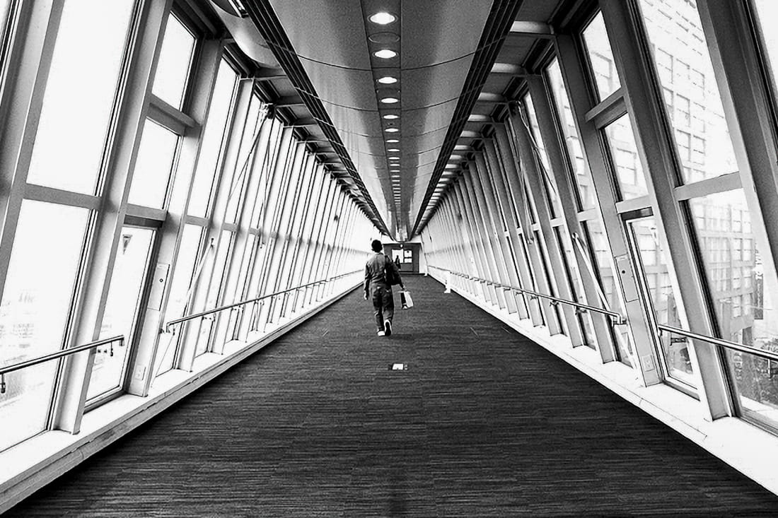 ガラス張りの渡り廊下を歩く男