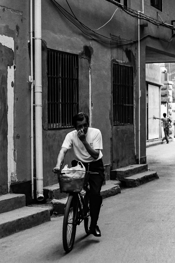 Man riding bicycle while scratching nose
