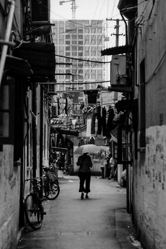 Woman walking putting umbrella up in lane