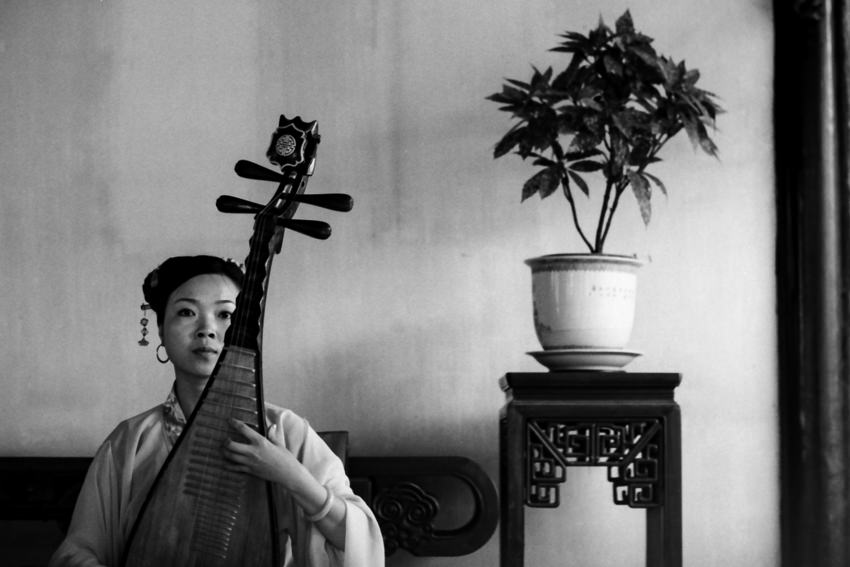 Woman playing Chinese lute with deadpan face