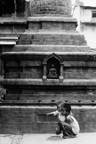 Boy looking after little brother in front of Buddha statue