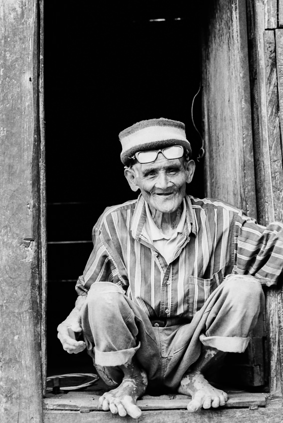 Old man crouching at door
