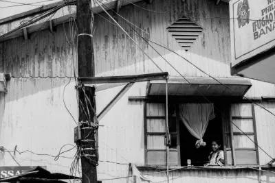 Woman watching bicycle race through upstairs wiindow