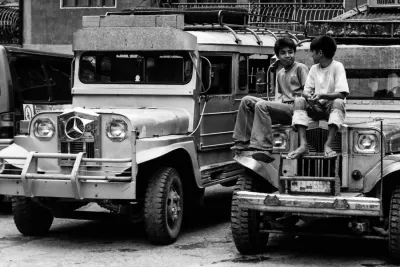 Two boys sitting on the hood of a jeepney