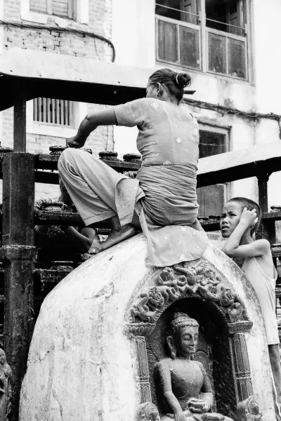 Woman sweeping while sitting on statue of Buddha