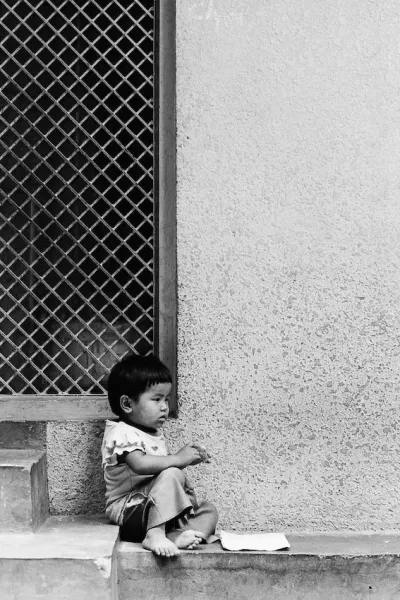 Little kid sitting alone under eaves
