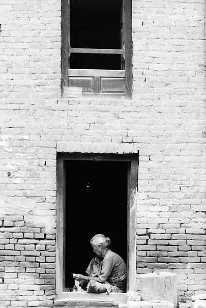 Older Woman Working At The Door (Nepal)