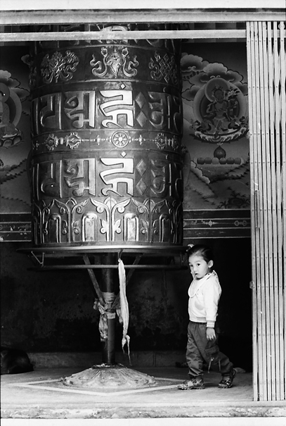 Little Girl Turing Around A Big Prayer Wheel (Nepal)