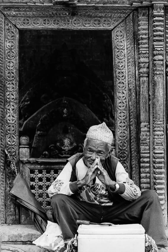 Old man sitting in front of small shrine