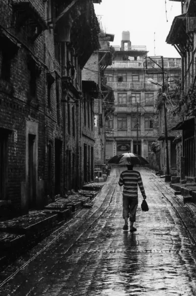 雨の中を傘を差して歩く男