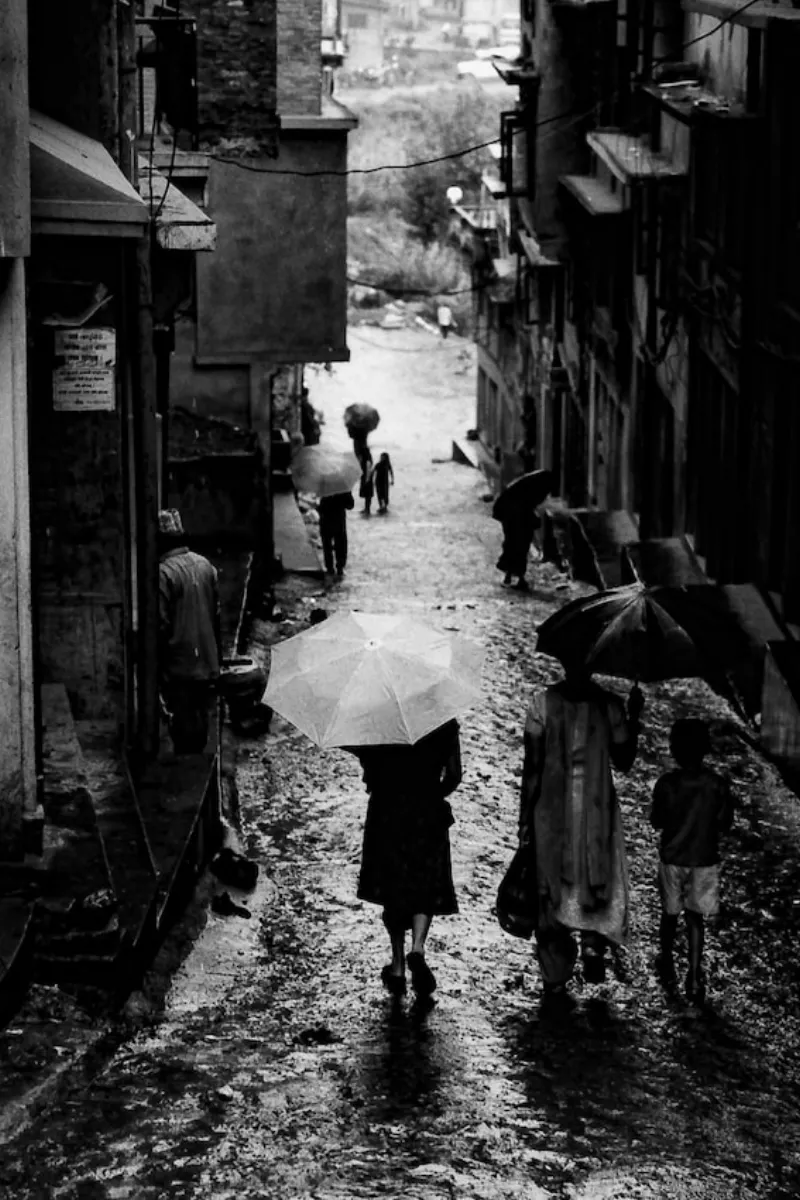 People walking with umbrellas on a wet slope