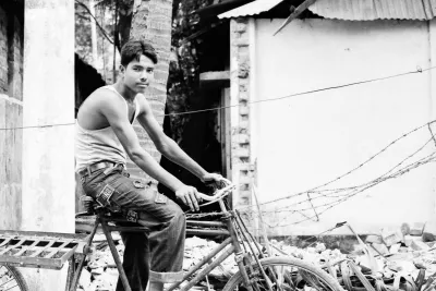 Young man astride a tricycle with a cargo bed