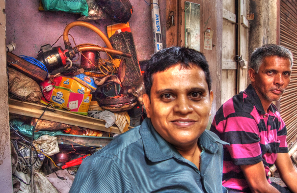 Two Men In Front Of A Junkyard (India)