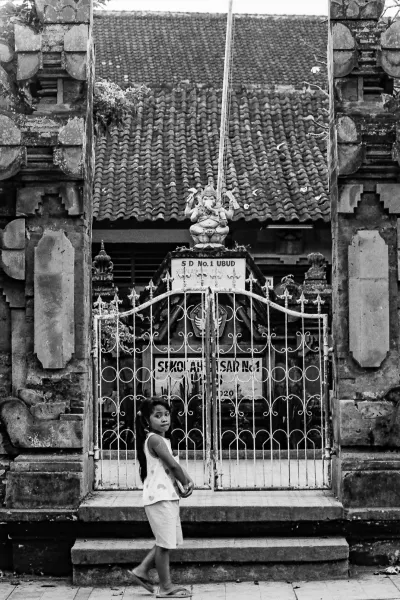 Girl walking in front of gate of school