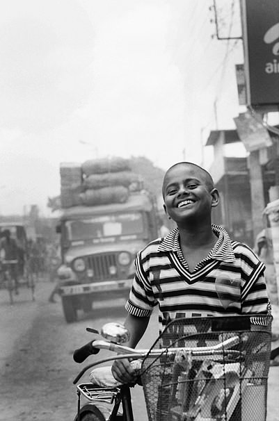 Smiling Boy Walking His Bicycle (India)
