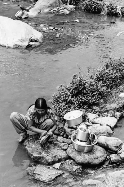 Woman washing dishes with river water