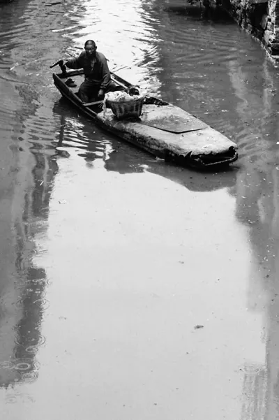 Man rowing a boat on a waterway in Suzhou