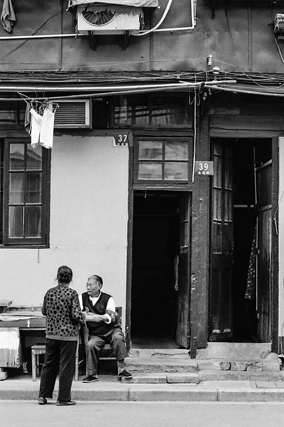 Old couple relaxing in front of house