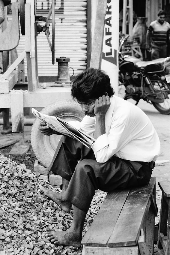 素足で新聞を読む男