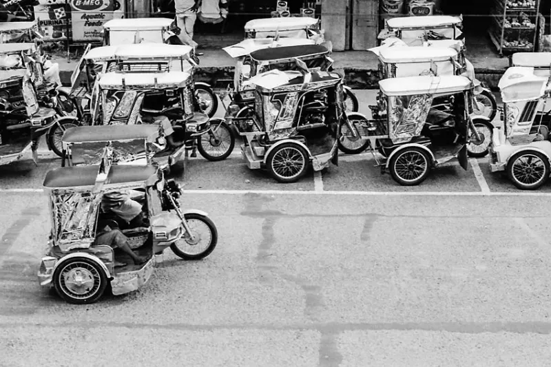 Parked trishaws and running trishaw