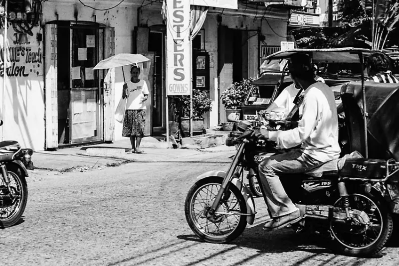 Woman standing with umbrella in crossing