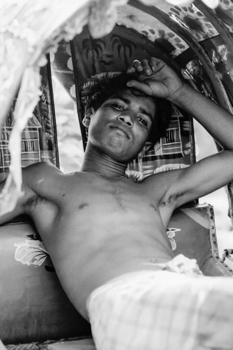 サイクルリクシャーの上で眠たそうにしていた青年