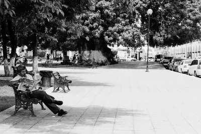 Man reading newspaper in the shade