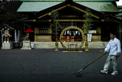 Shinto priest raking graveled precinct