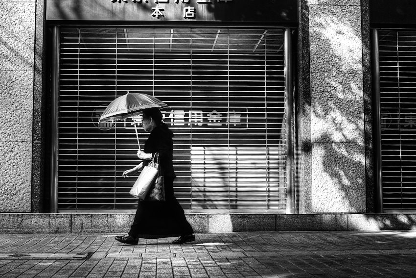 Older woman putting umbrella up