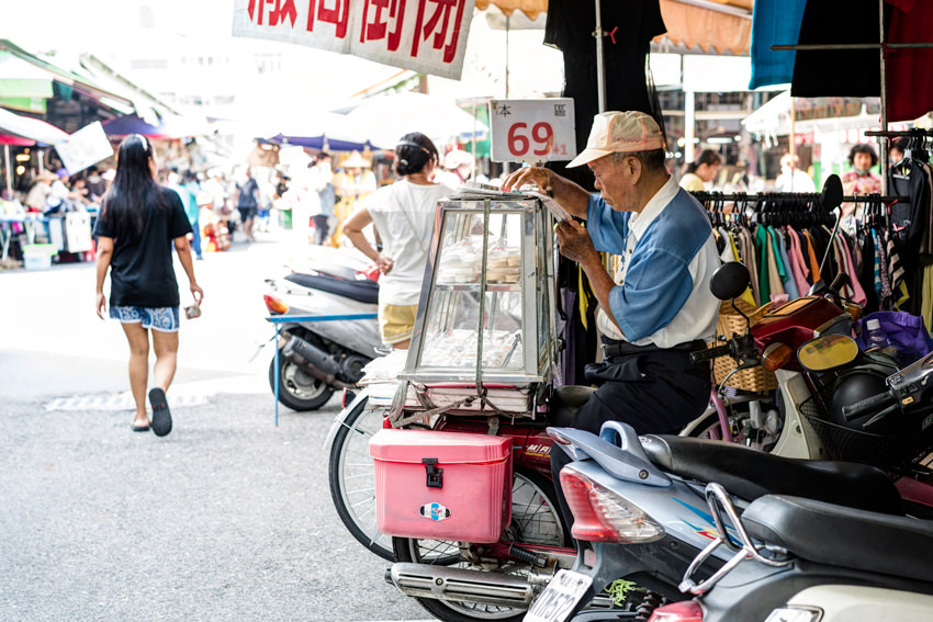 Old man reading newspaper by wayside