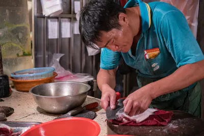 Fishmonger filleting fish into three pieces