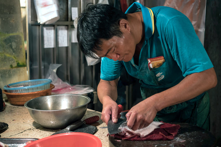 Fishmonger filleting fish into three pieces