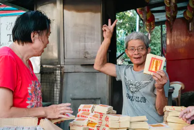 Man making a peace sign with joss papers in his hand