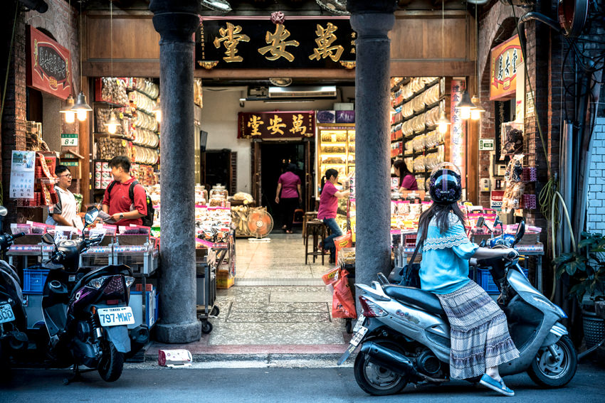 Young woman on motorbike stopping in storefront