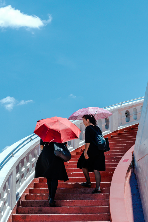 Women climbing red stairway in Wat Saket