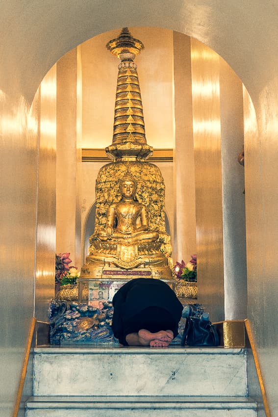 Woman bowing down on knees in Wat Saket