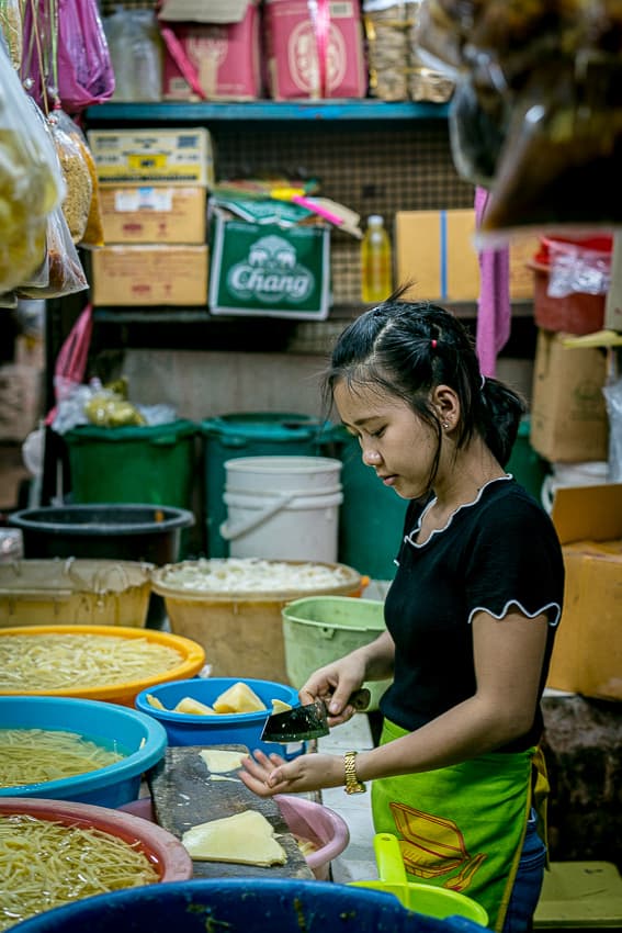 Young woman cutting vegetables in Khlong Toei Market