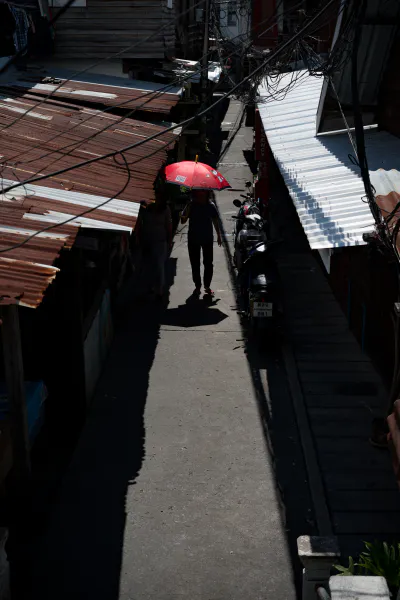 Figure with red umbrella walking between zinc roofs