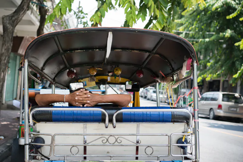 Man resting in the back seat of a tuk-tuk