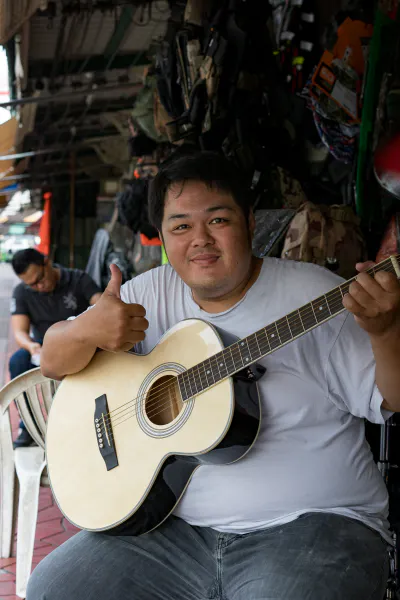 Young man thumbing up while holding guitar