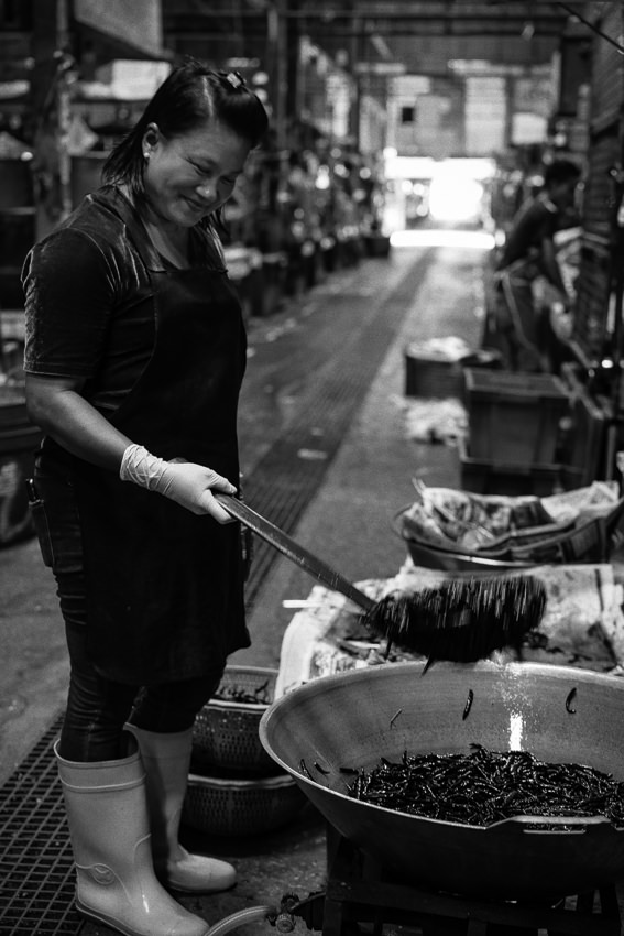 Woman cooking red peppers in big wok
