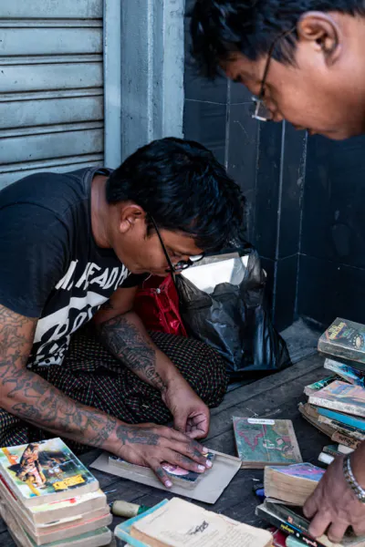 Man repairing an used book by the wayside