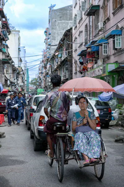 自転車タクシーの上で傘を差す女性